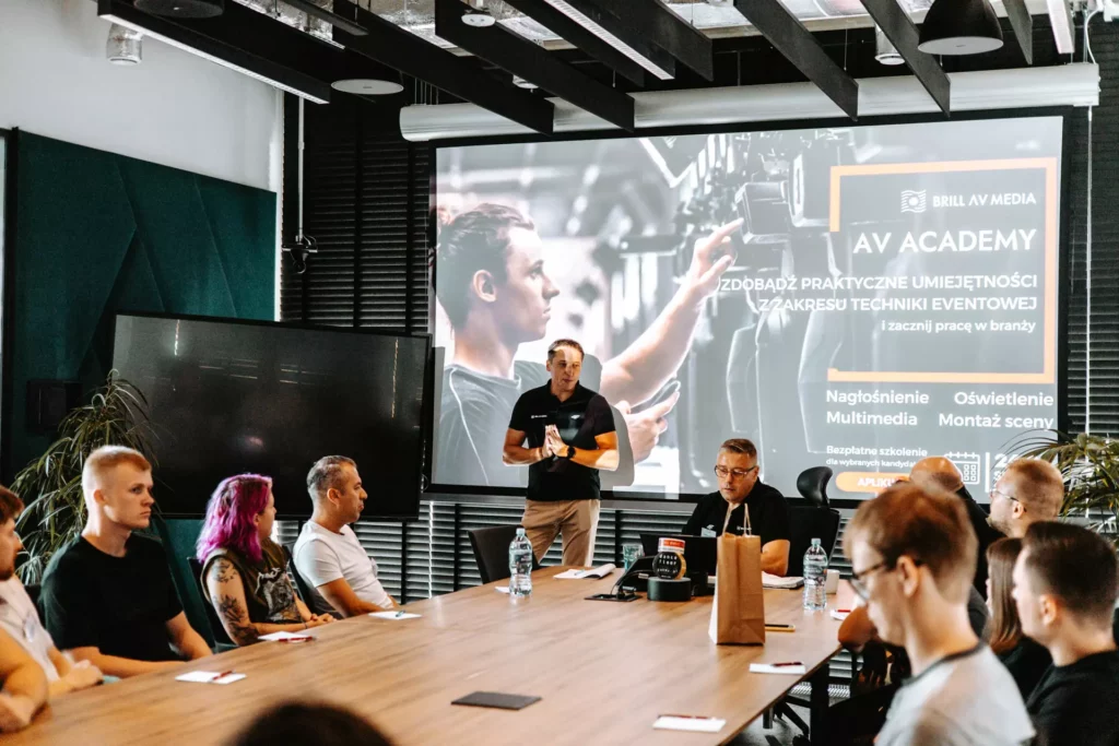 Prezentacja "AV Academy" o kursach techniki eventowej przed grupą uczestników.