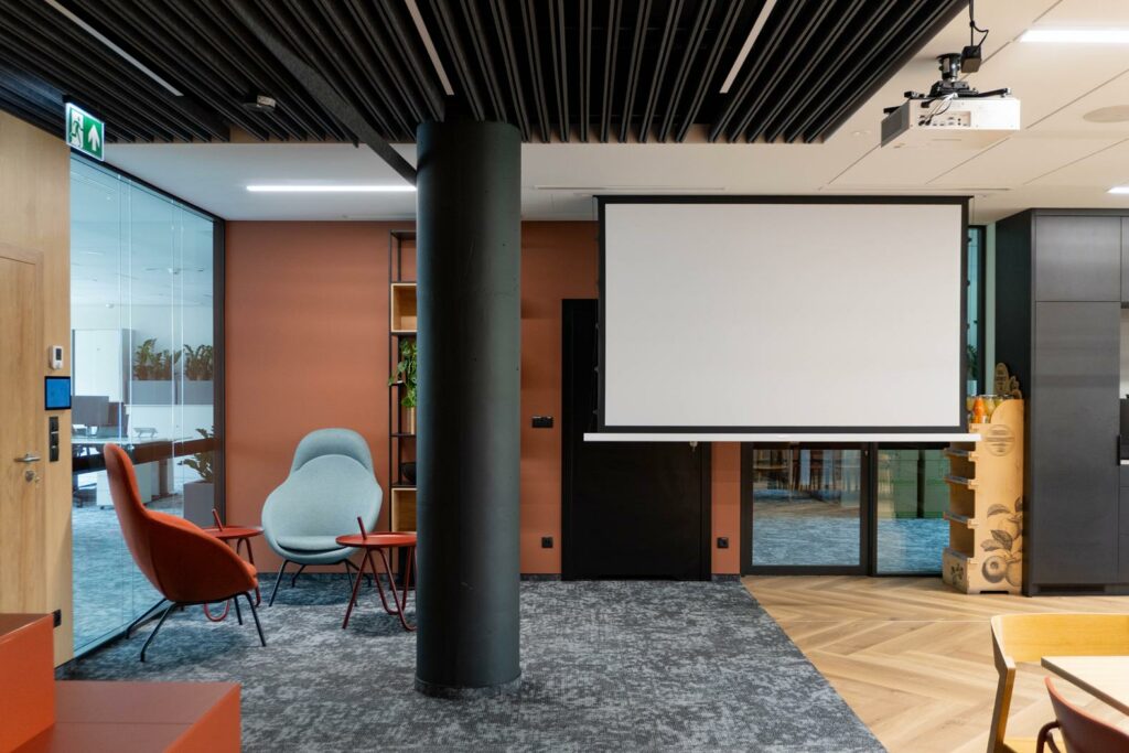 Strefa lounge z ekranem projekcyjnym i nowoczesnymi fotelami
