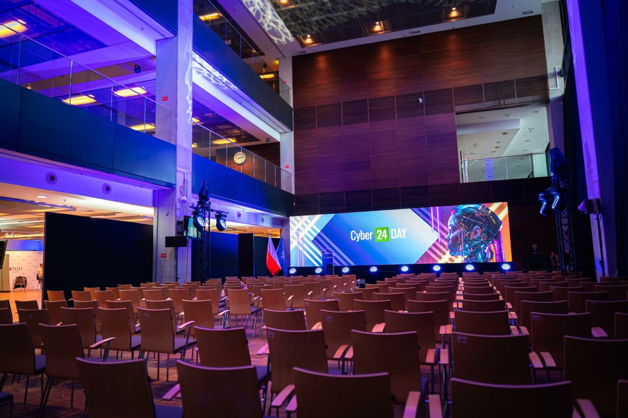 Pusta sala konferencyjna Cyber24Day z przygotowaną sceną i oświetleniem